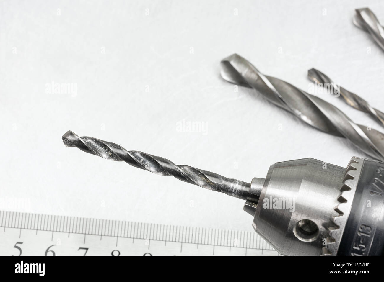 Electric drill head with drill bits on scratched metal background Stock Photo