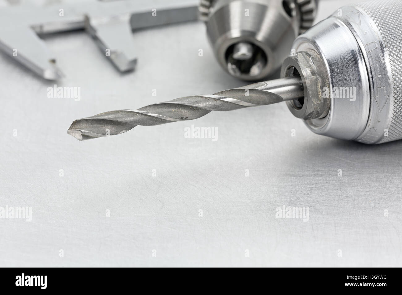 Electric drill chuck with drill bits and vernier caliper on metal