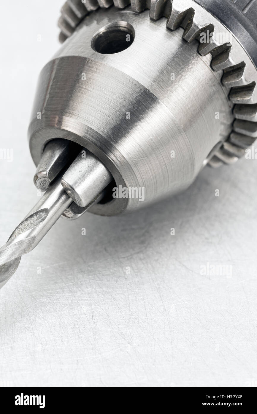 Electric drill head with drill bit on scratched metal background closeup Stock Photo