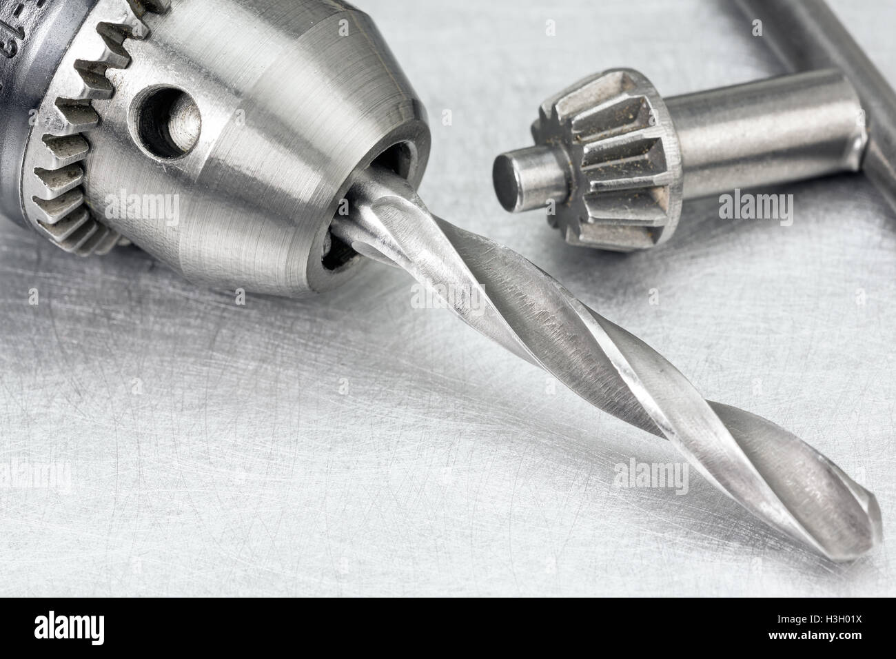 Electric drill head with drill bit and drill key on scratched metal