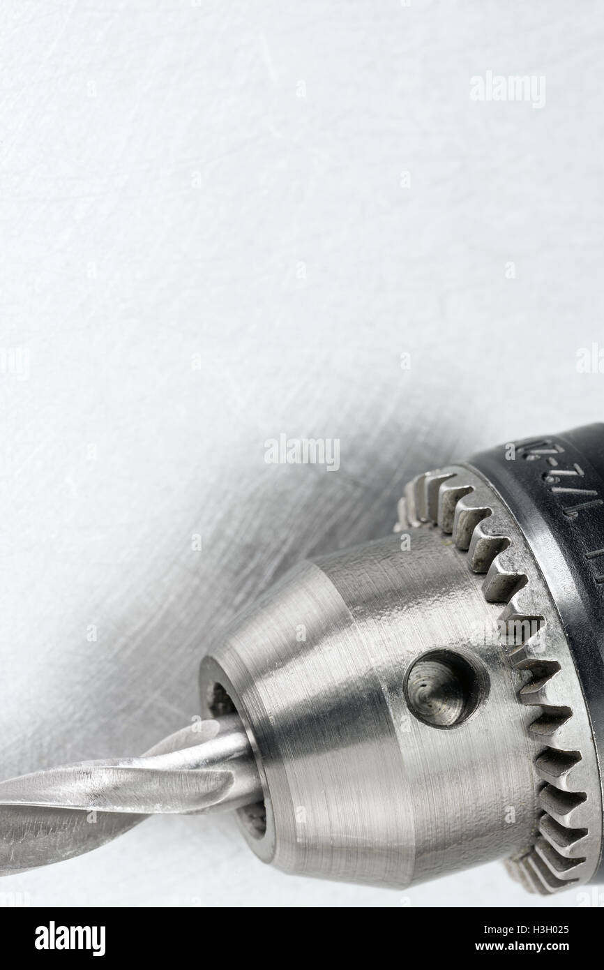 Electric drill head with drill bit on scratched metal background Stock Photo