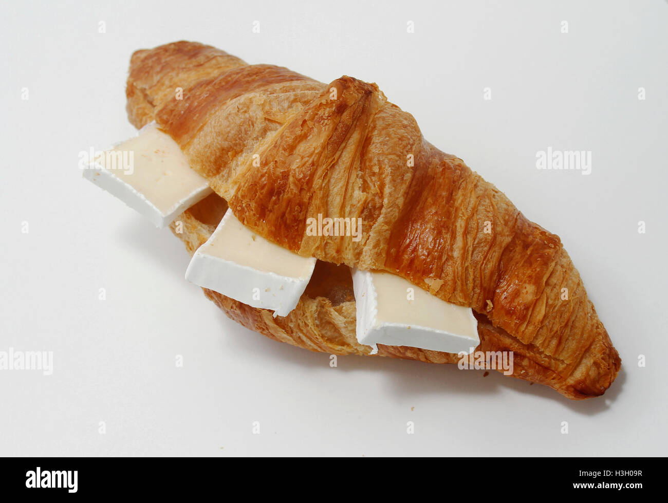 Fresh croissant with three slices of brie cheese. Stock Photo