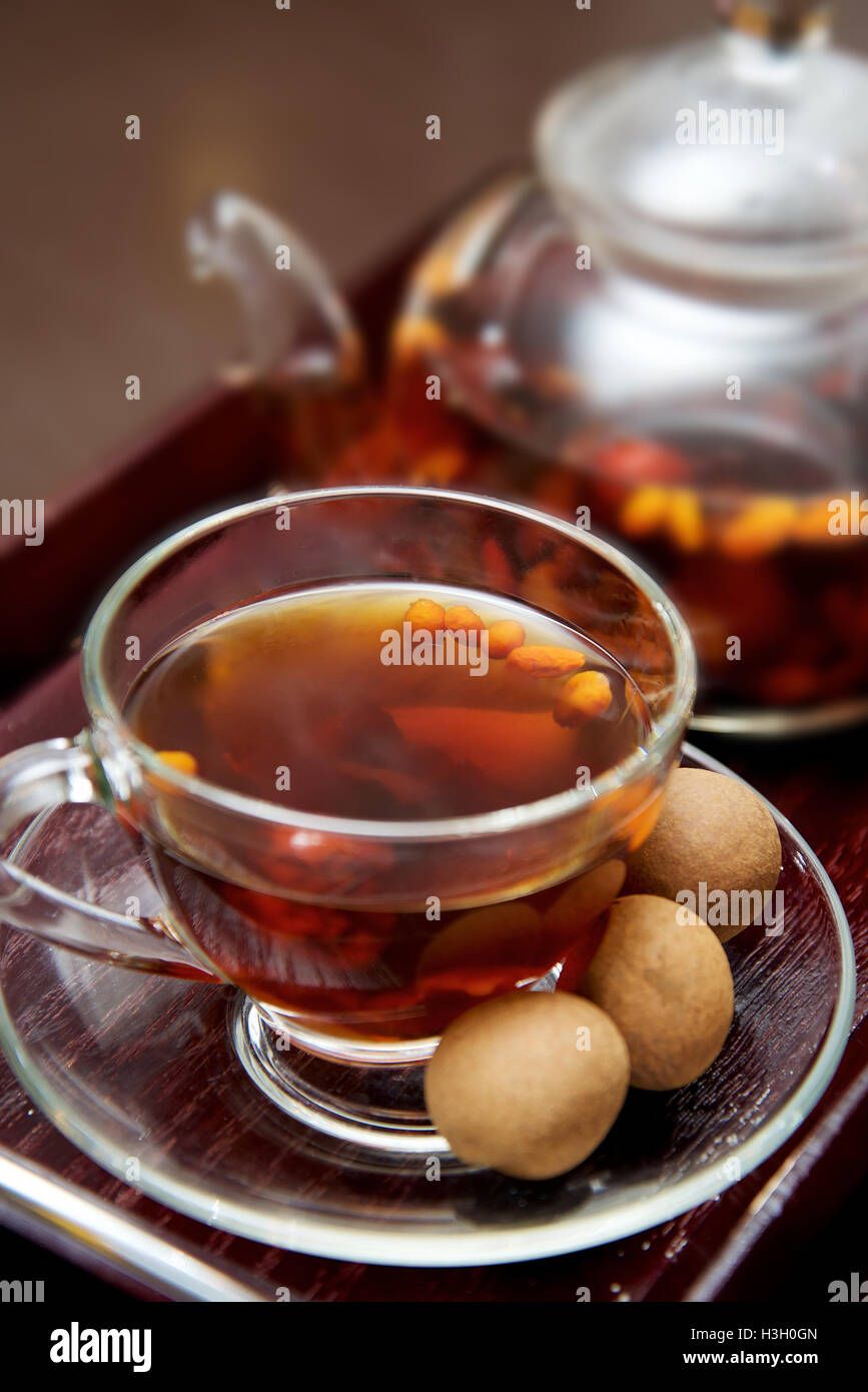 Glass teapot with blooming green tea and cup of tea on dark background Stock Photo