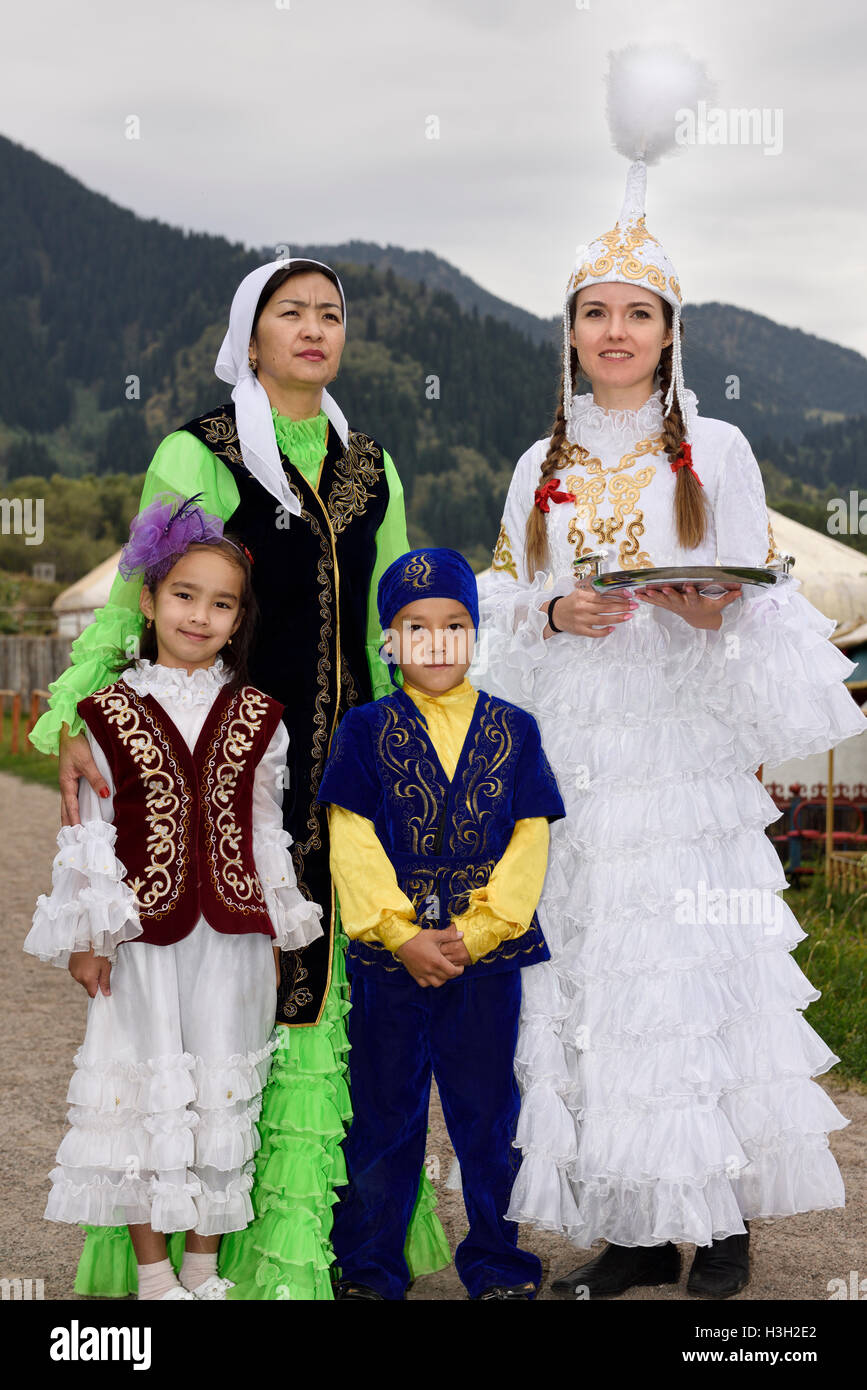 Women and children in traditional Kazakh clothes greeting quests with Shashu candies at Huns village Stock Photo
