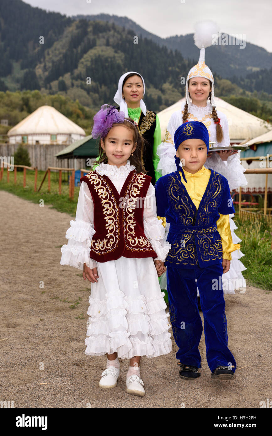 Women and walking children in traditional Kazakh clothes greeting quests with Shashu candies at Huns village Stock Photo