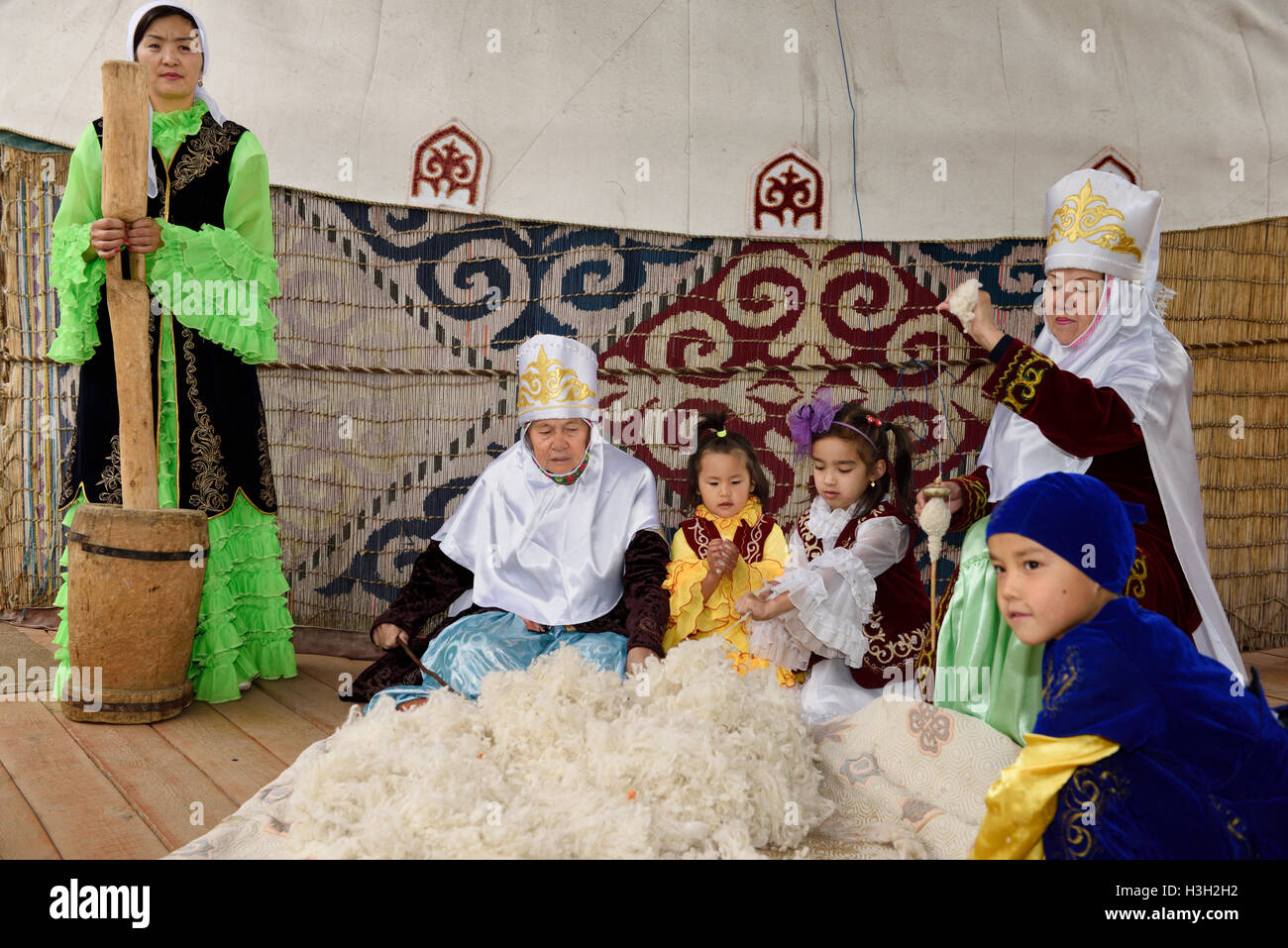 Women and children in traditional Kazakh clothes working wool into ...