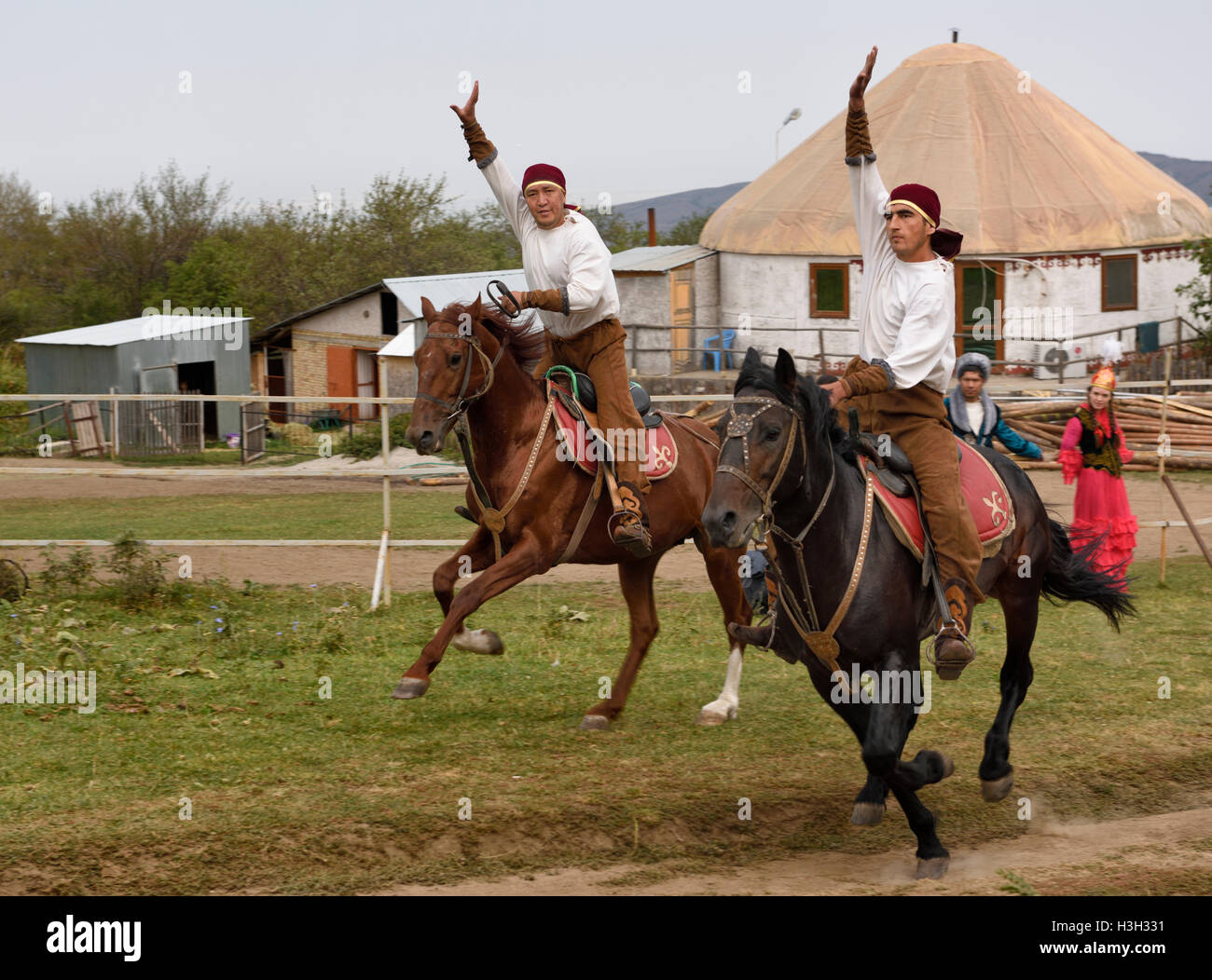 Kazakh horse riders galloping past with arms raised in Huns Village Kazakhstan Stock Photo