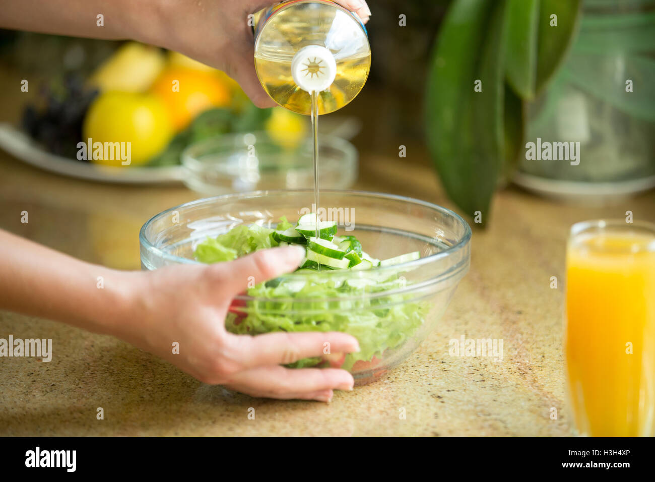 Hands pouring oil in a green salad Stock Photo