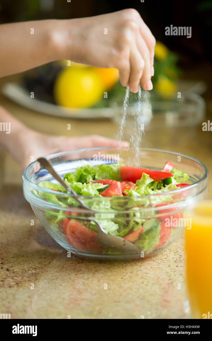 Hands salting a green salad Stock Photo