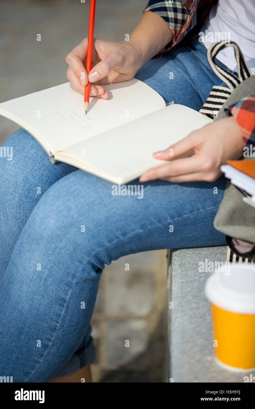 Student lady writing in an open notebook with a pencil Stock Photo