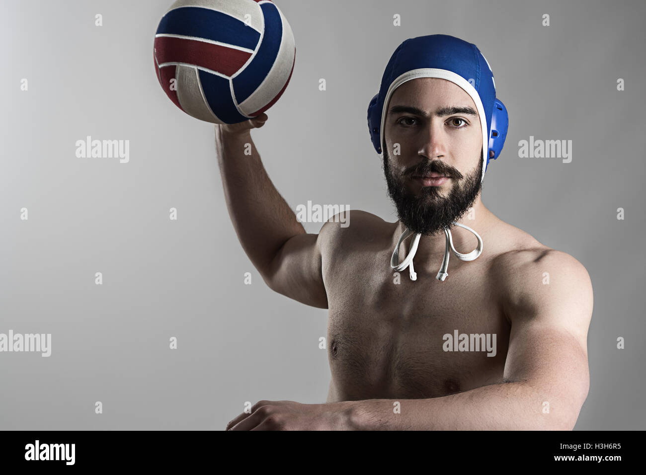 Professional water polo player shooting ball looking at camera over