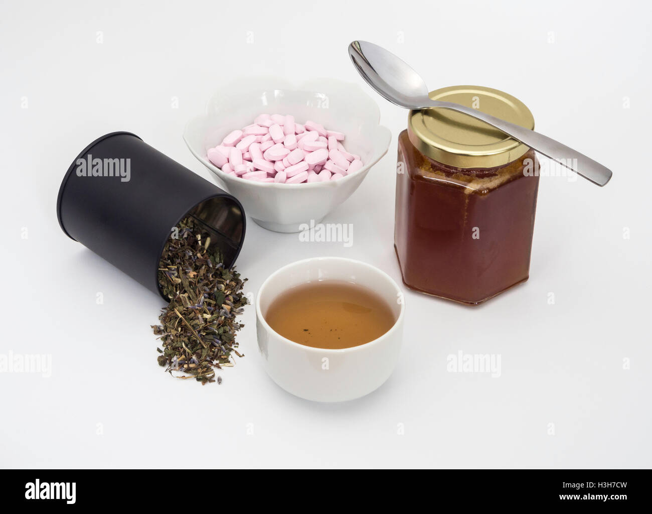 Green herb tulse with cup of tea, Vitamin B12 tablets and jar of chestnut honey, a combined remedy for cold and flu season. Stock Photo