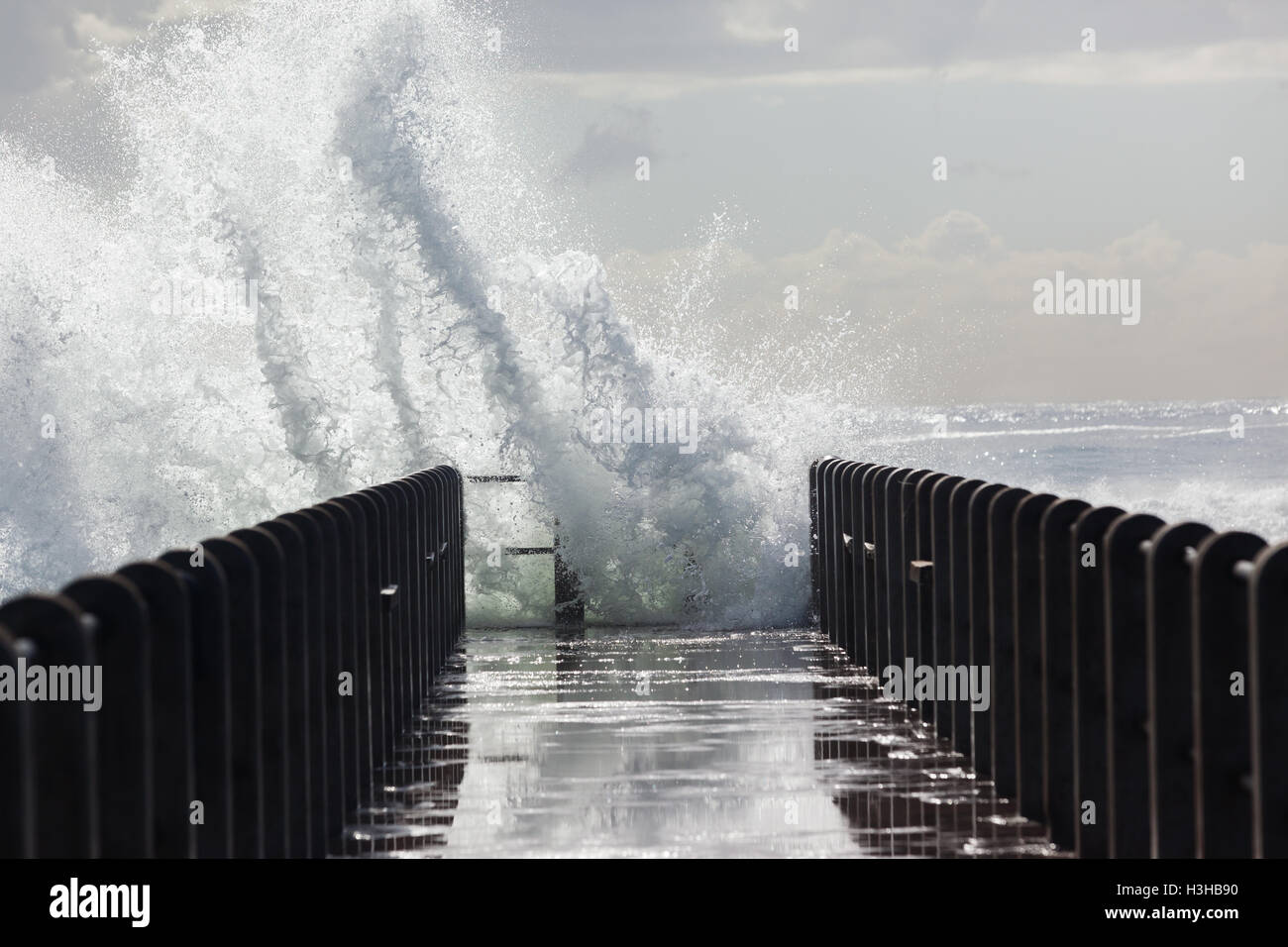 Beach pier jetty with ocean storm waves crashing with water power. Stock Photo