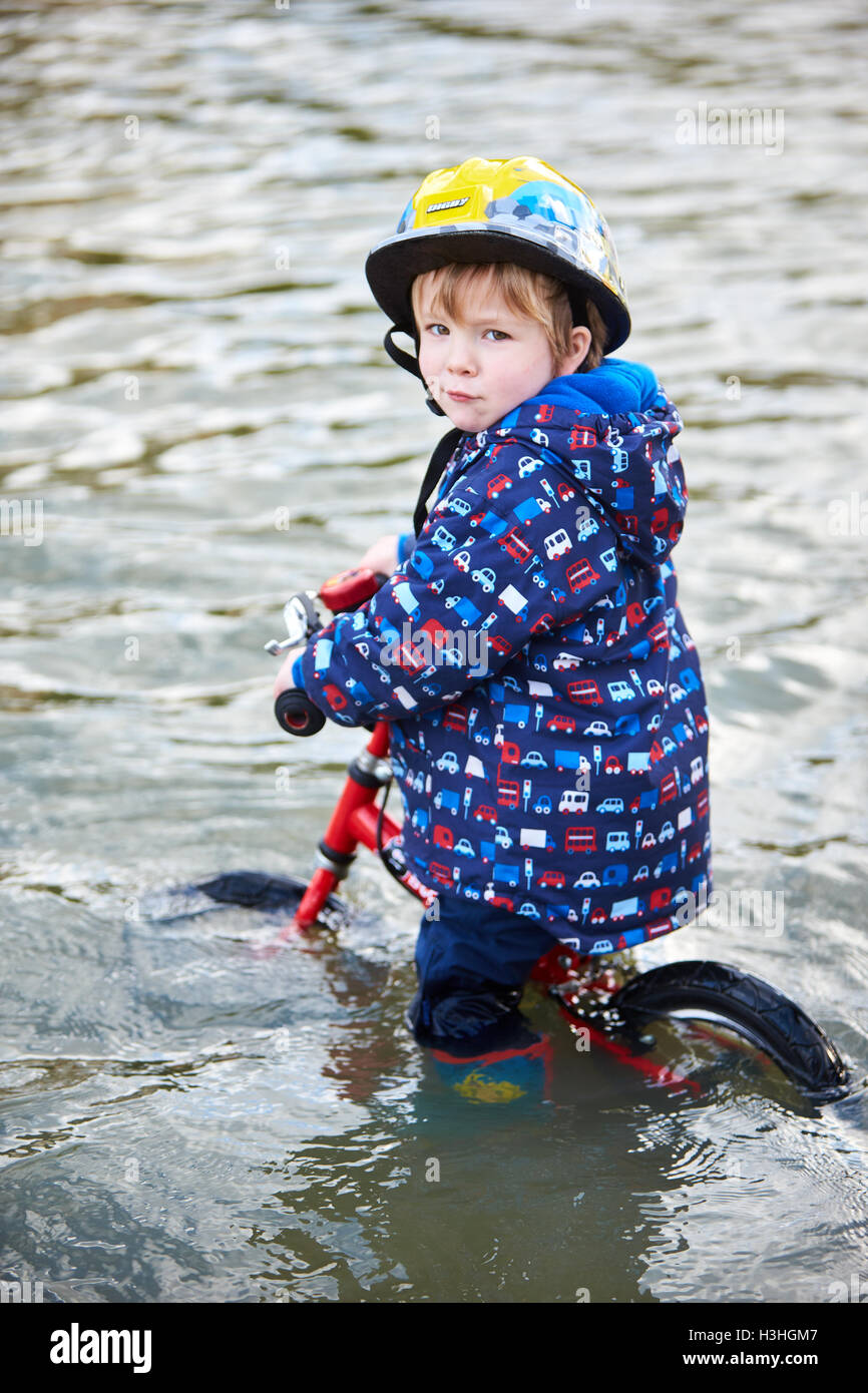 A young boy tries to cycle through flood water on Abingdon Road in