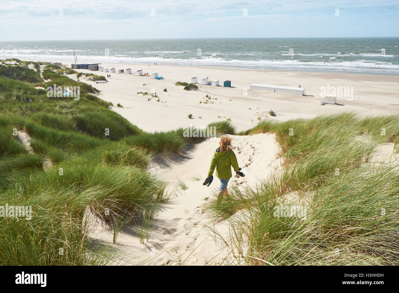 woman-walking-through-the-sand-dunes-at-the-beach-of-oostkapelle