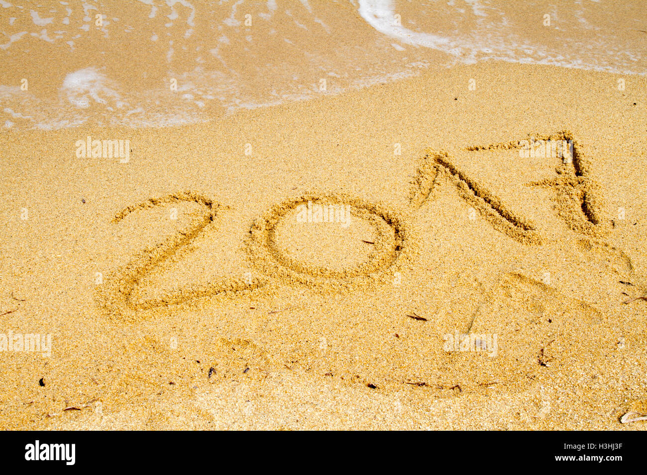 2017 written on empty wet yellow beach sand washed by sea wave. Stock Photo