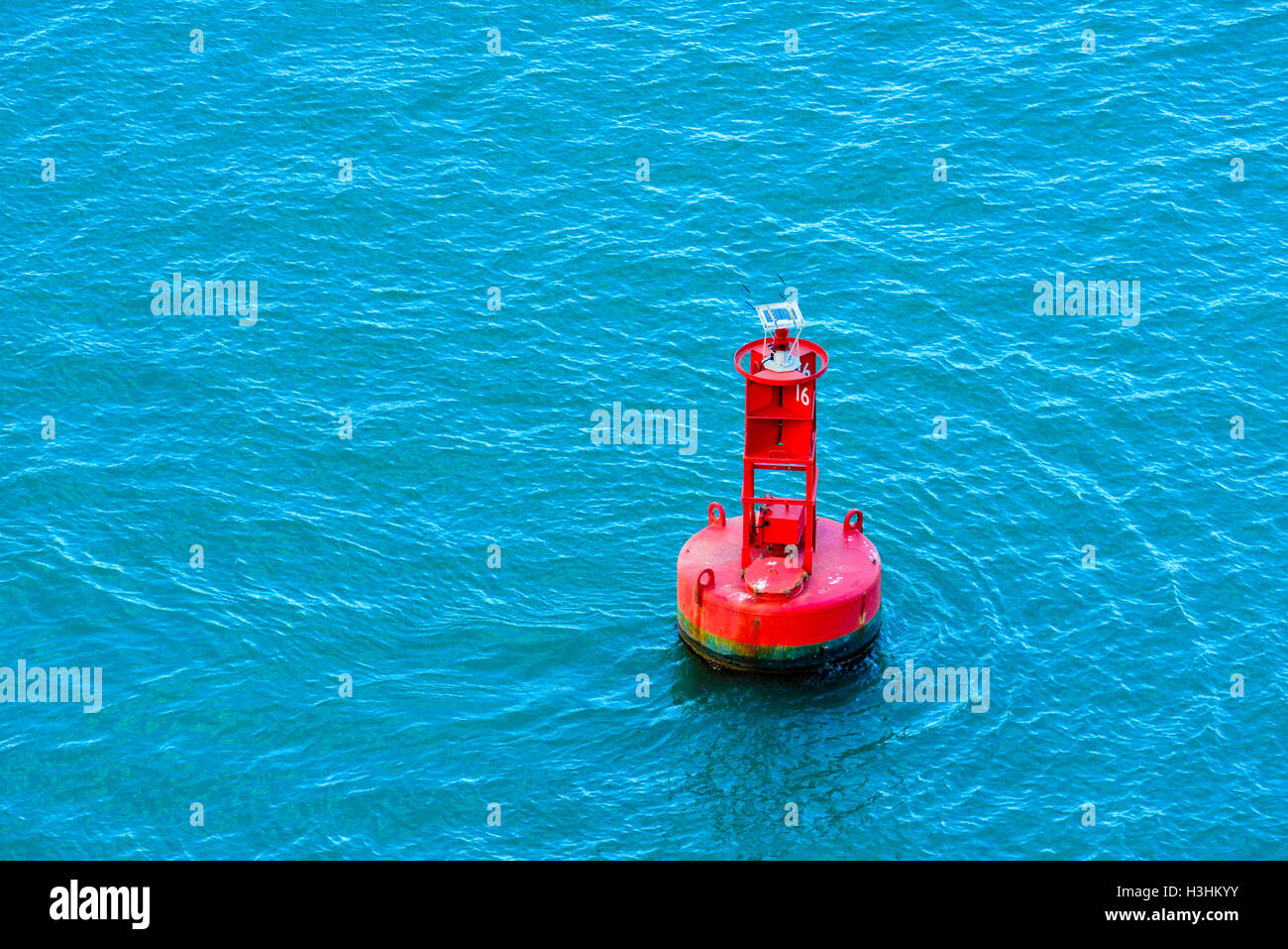 A bright red buoy floating in a blue ocean Stock Photo