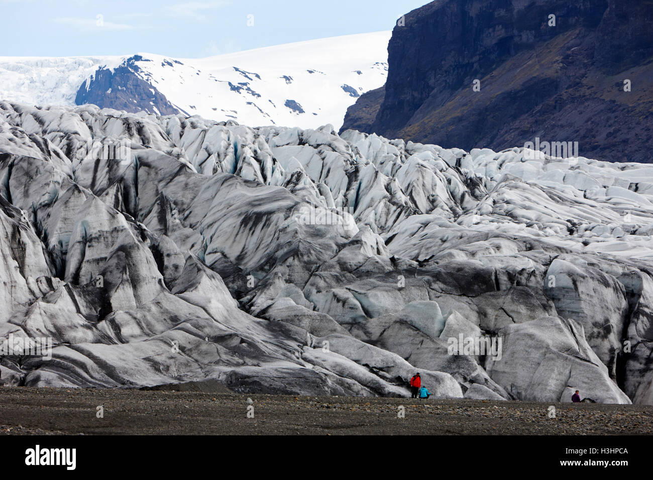 tourists at ash covered Skaftafell glacier and end moraine Vatnajokull national park in Iceland Stock Photo