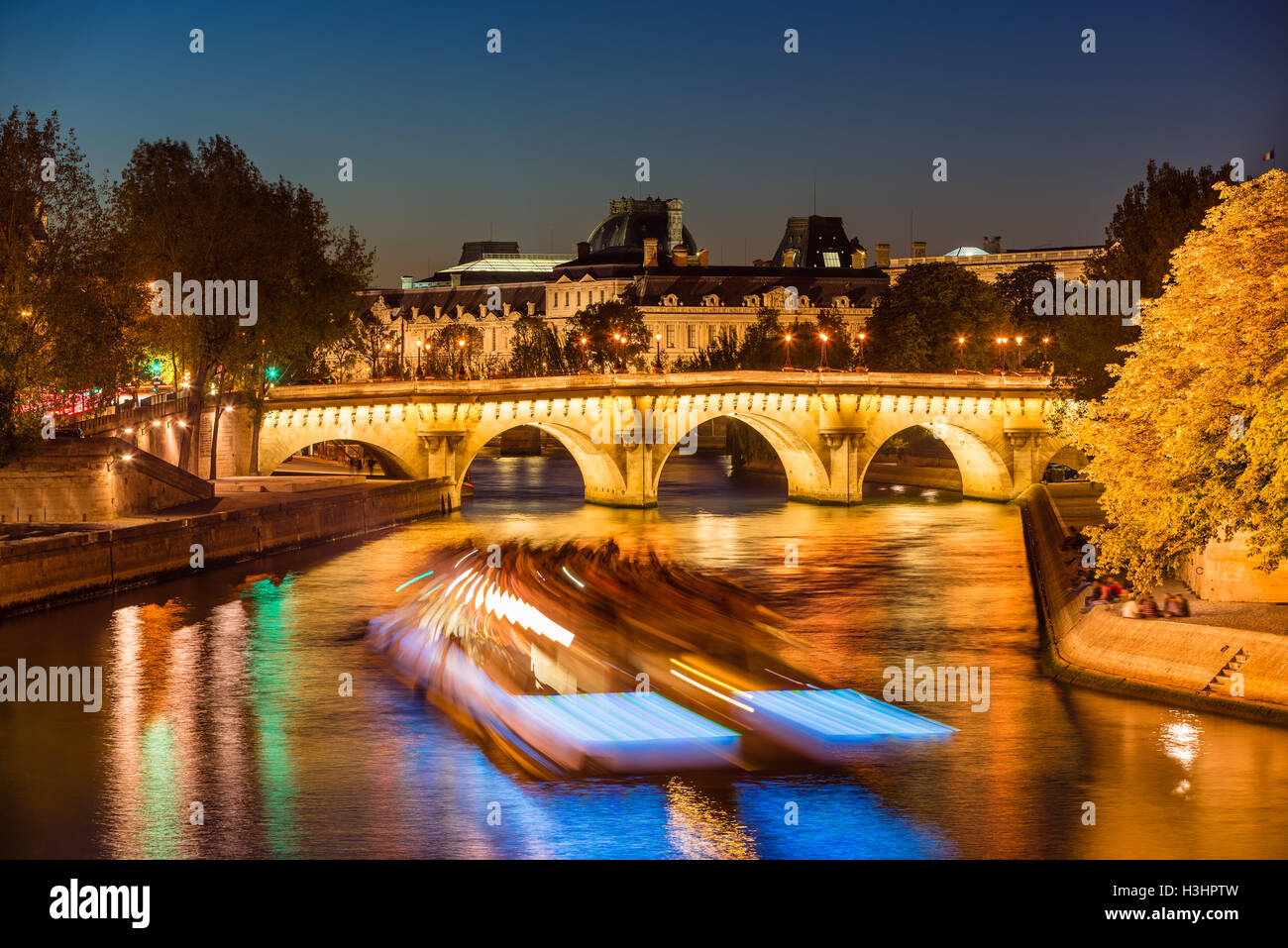 Pont Neuf bridge illuminated and Seine River at twilight with city lights and tourist boat. Ile de la Cite, Paris, France Stock Photo