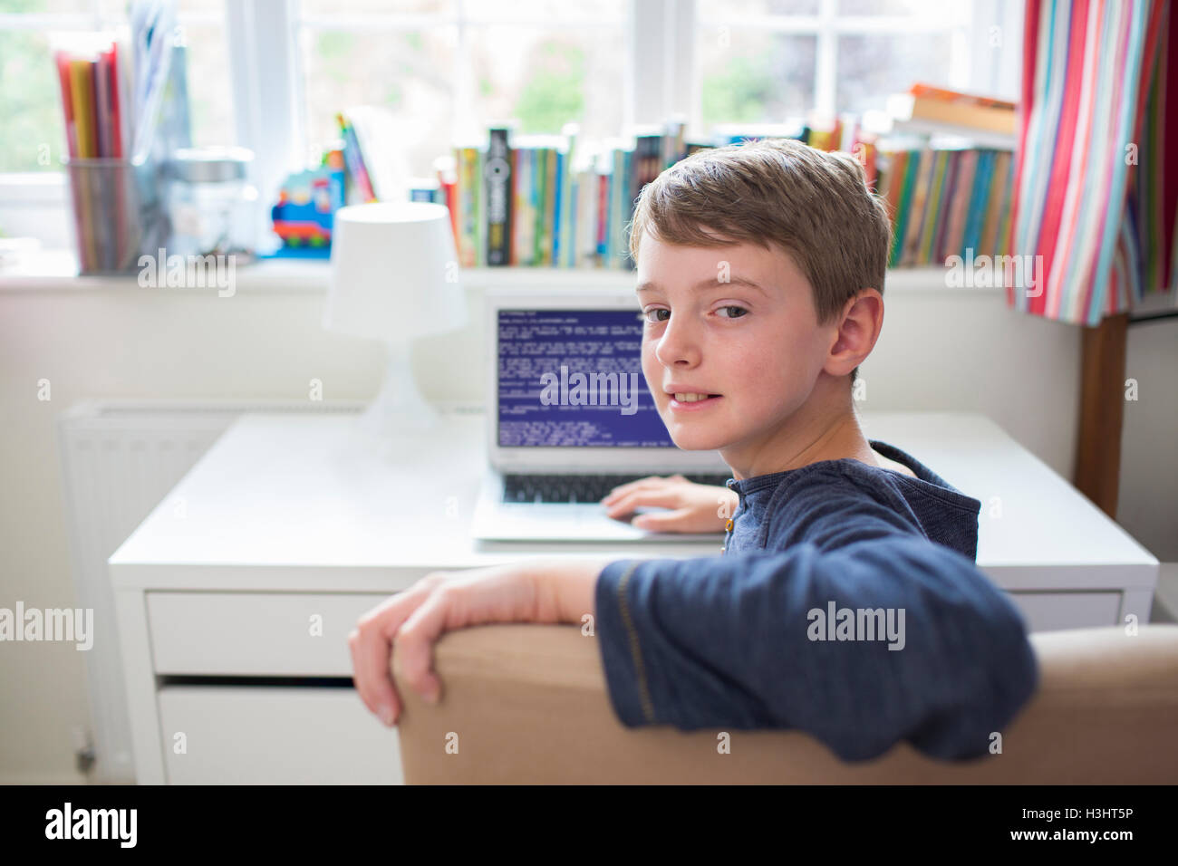 Teenage Boy In Bedroom Writing Computer Code Stock Photo