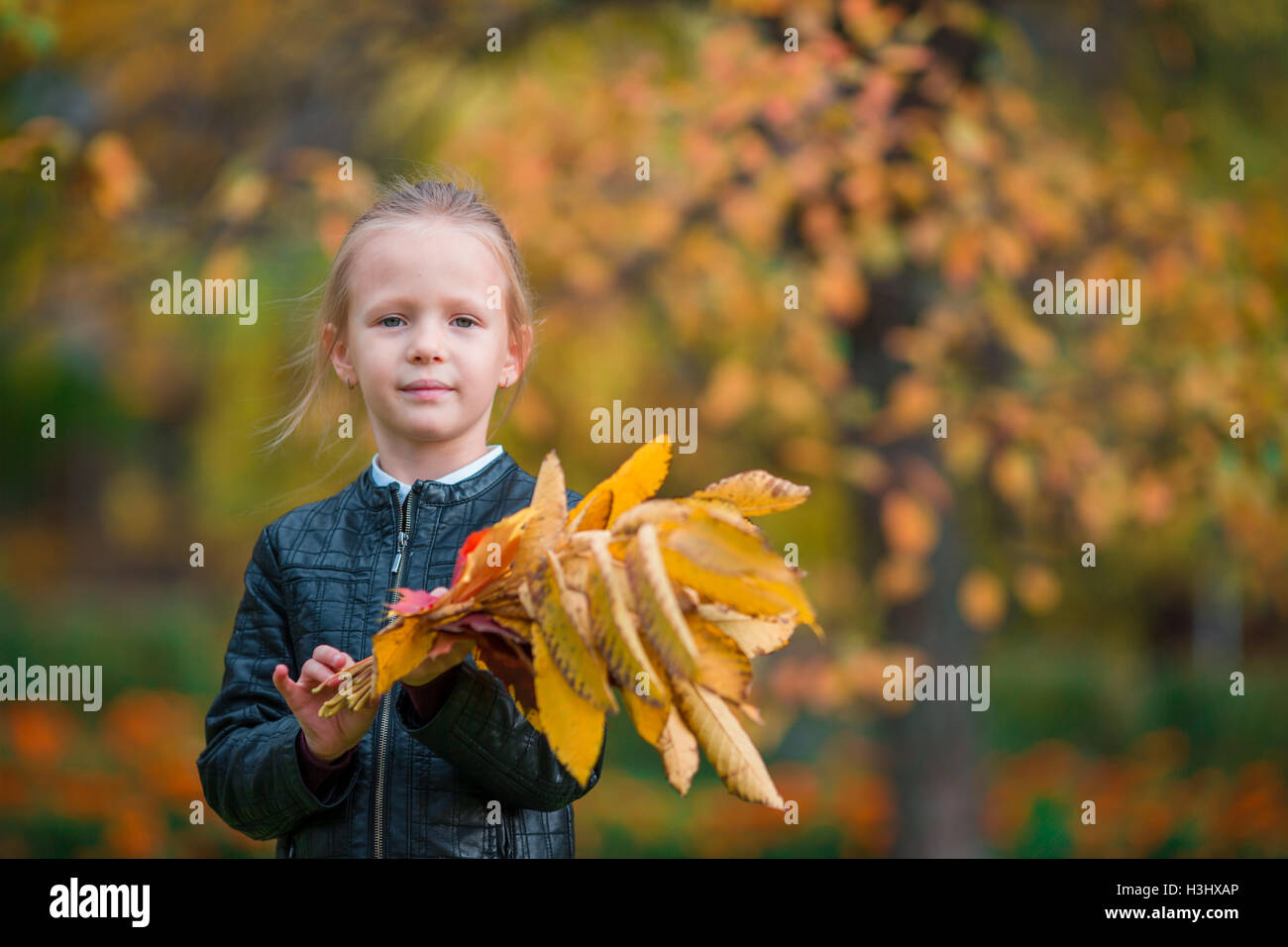 Portrait of adorable little girl with yellow and orange leaves bouquet ...