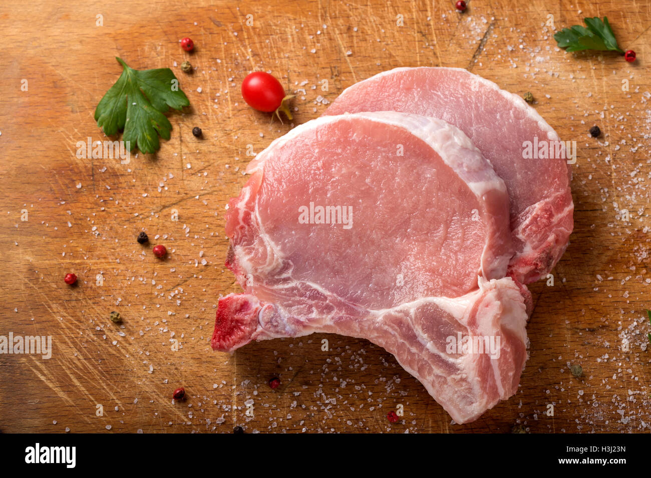 Fresh raw pork chops on a cutting board with herbs Stock Photo