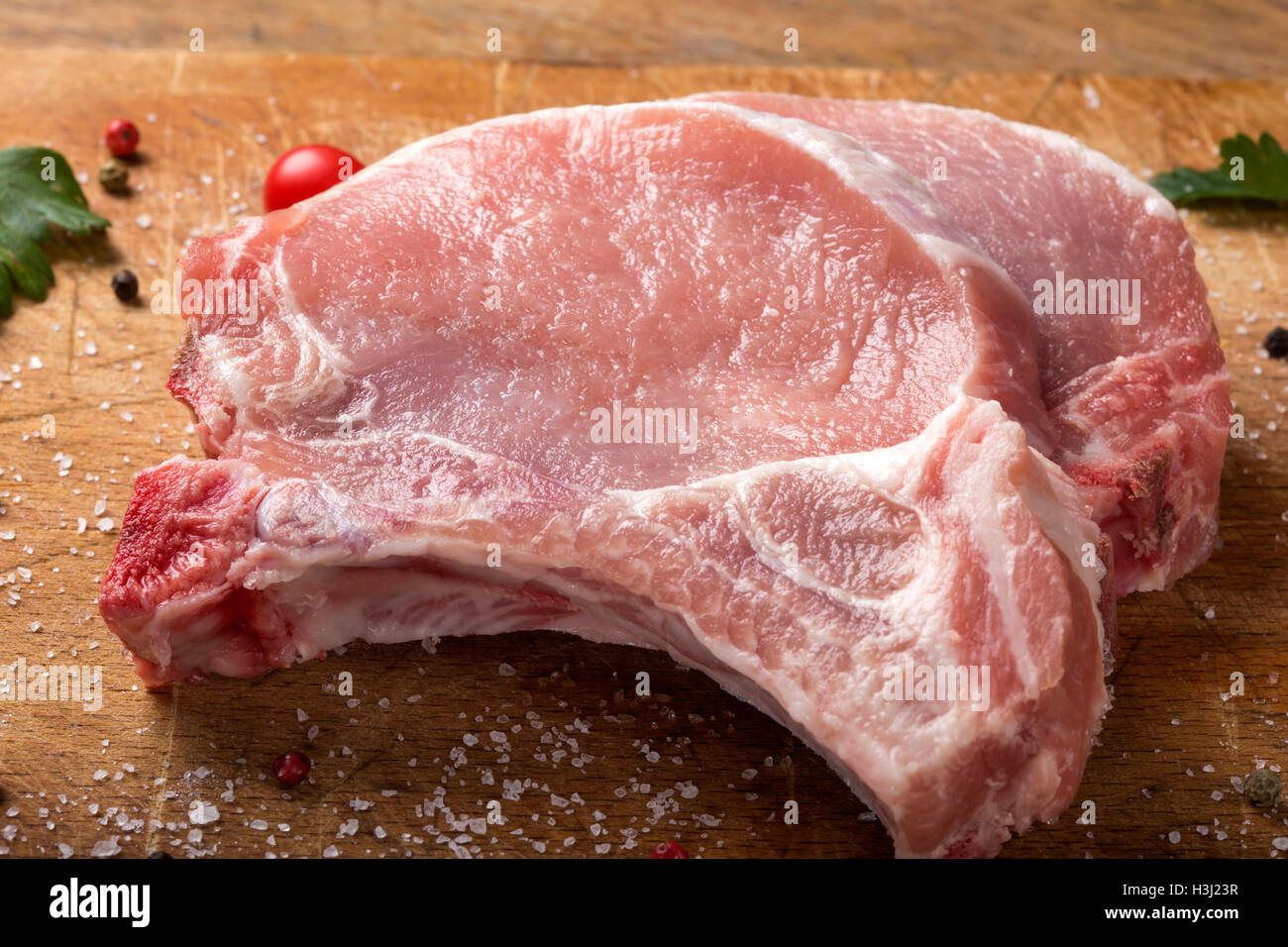 Fresh raw pork chops on a cutting board with herbs Stock Photo