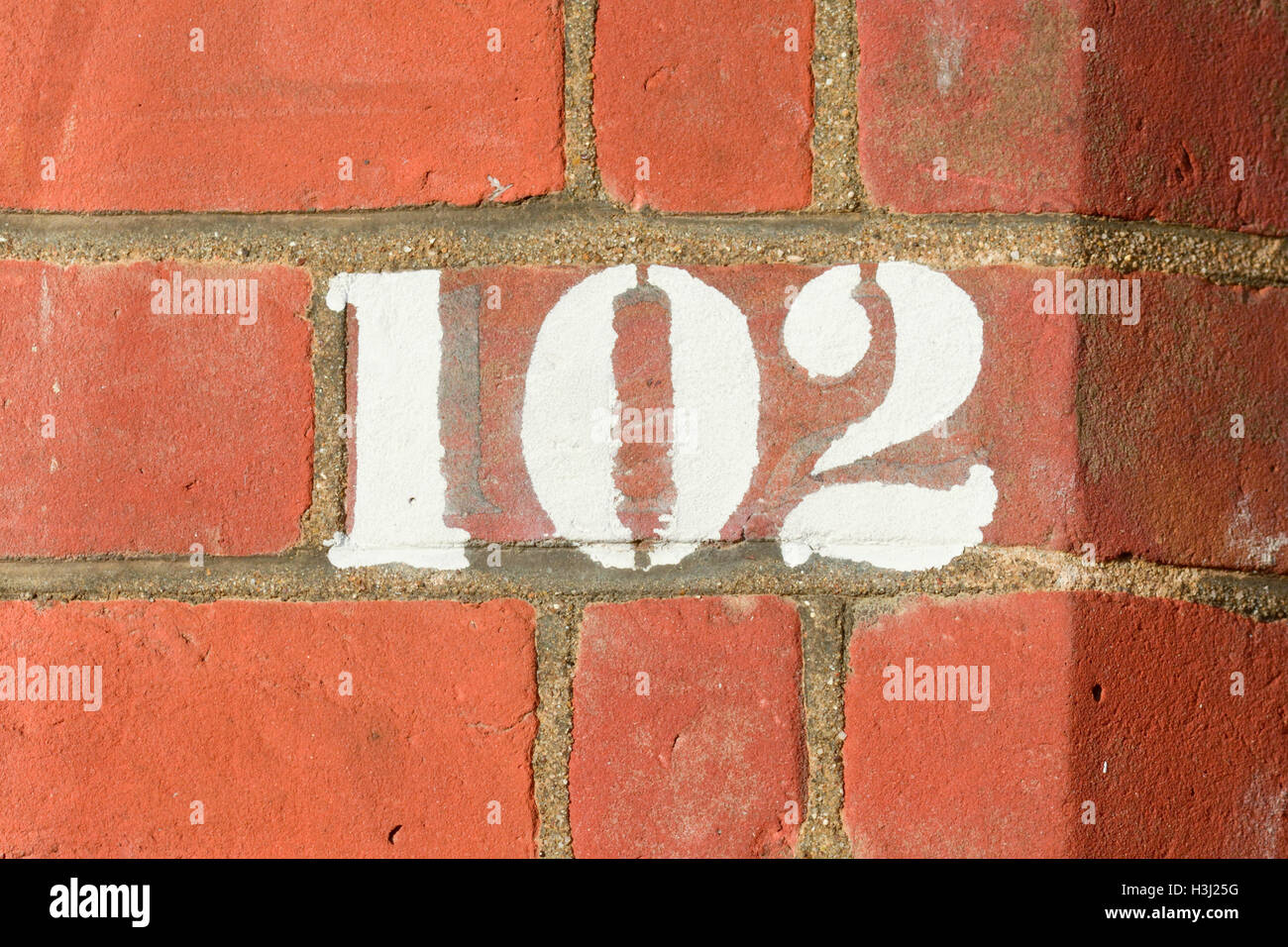 House number 102 sign painted on wall Stock Photo