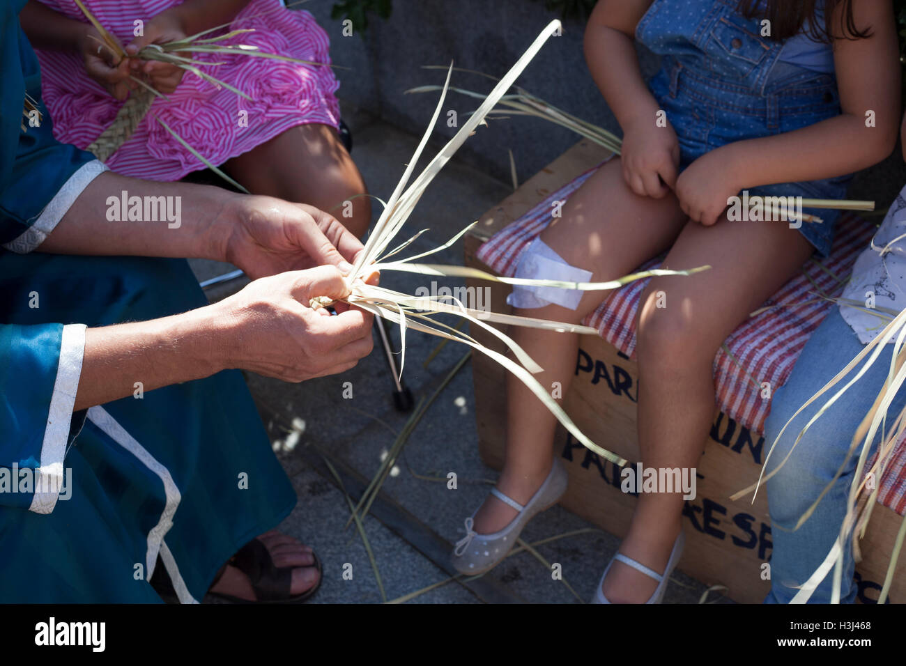 Badajoz, Spain - September 24, 2016: Artisan teaching children to plait vegetable fibers Stock Photo