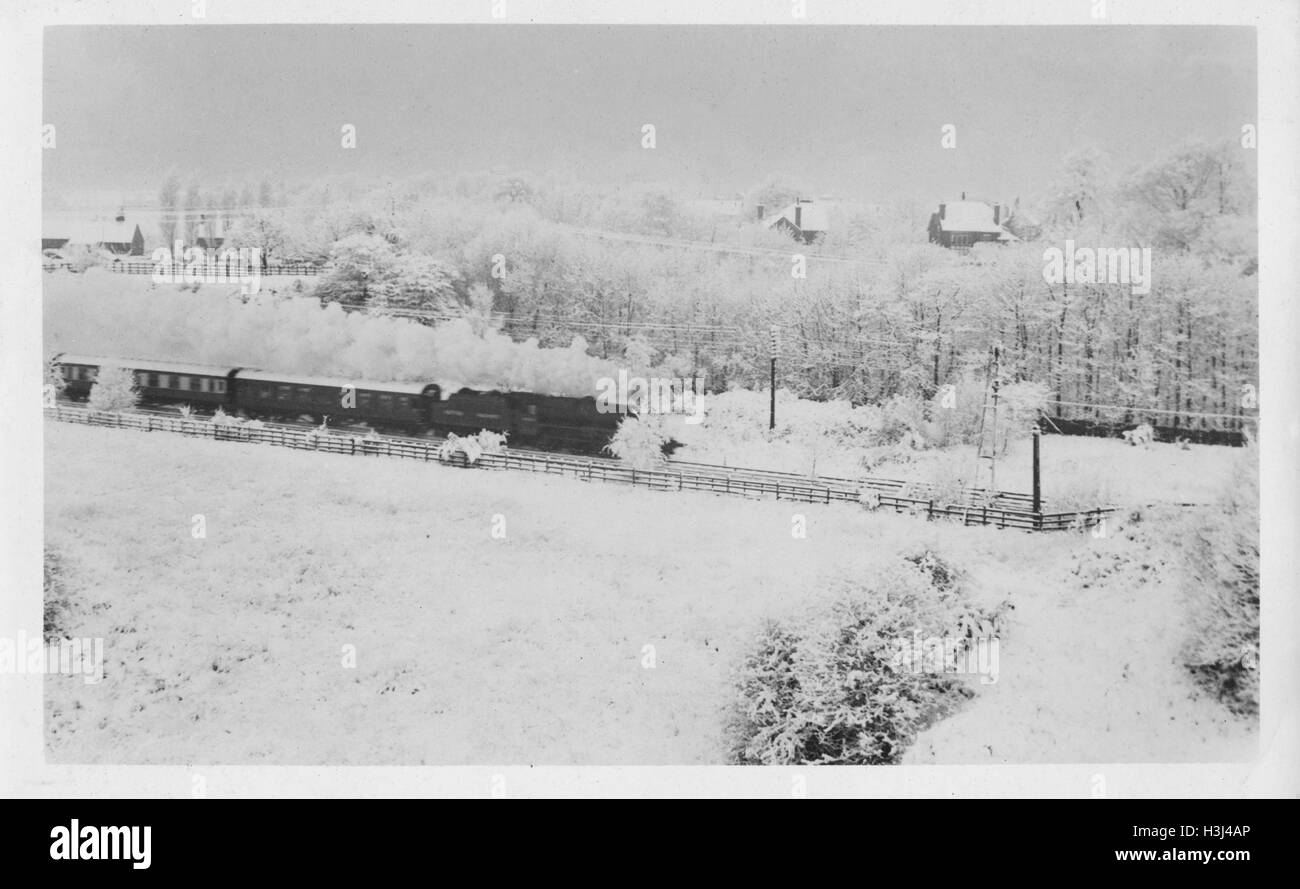 Steam train (GWR 6000 Class) and carriages rushing through a snow bound landscape in the winter. Photographed 12th December 1950 near Aughton Park Lancashire Stock Photo