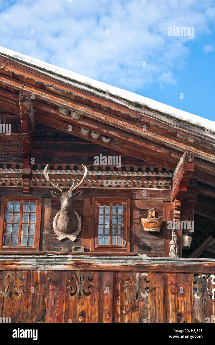 Detail of traditional wooden swiss house in winter, with some decoration such as a stuffed reindeer head. Stock Photo