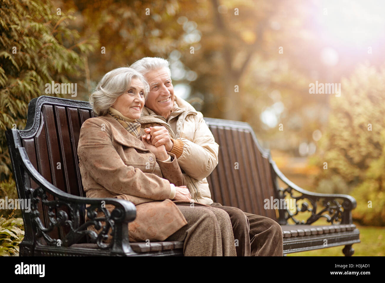 Happy elderly couple sitting on a bench in autumn park Stock Photo - Alamy