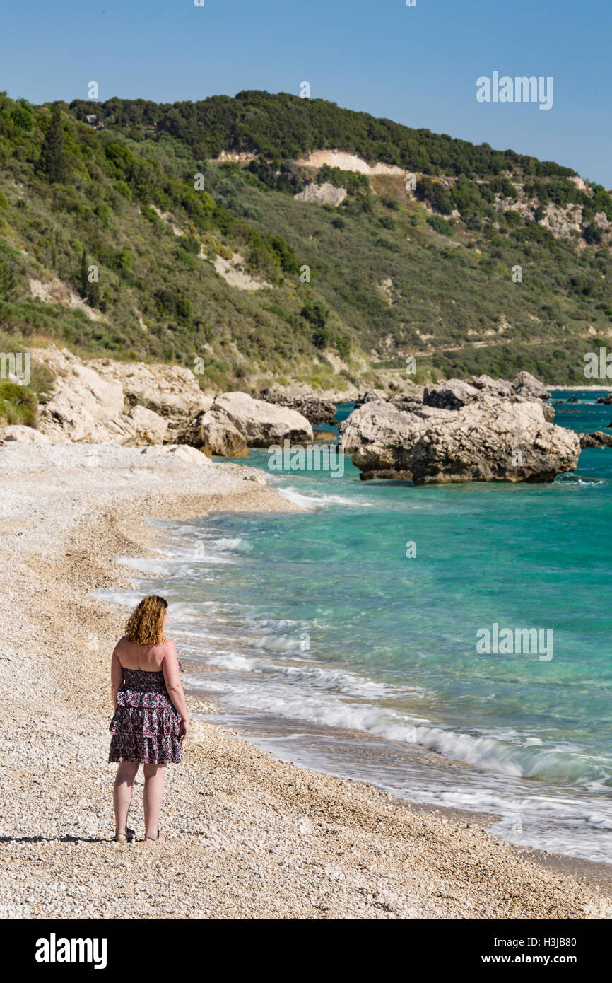 A lady stands on the beach at Poros, Kefalonia, looking out to sea. Stock Photo