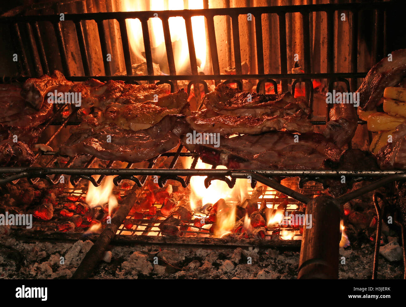 cooking the meat on the grill in the big fireplace in the restaurant Stock Photo