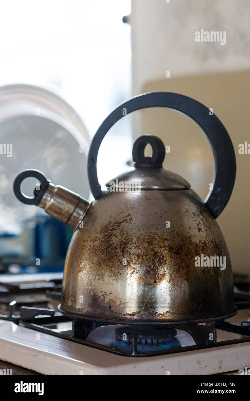 Old stainless steel kettle boiling on gas stove in caravan (trailer). Stock Photo
