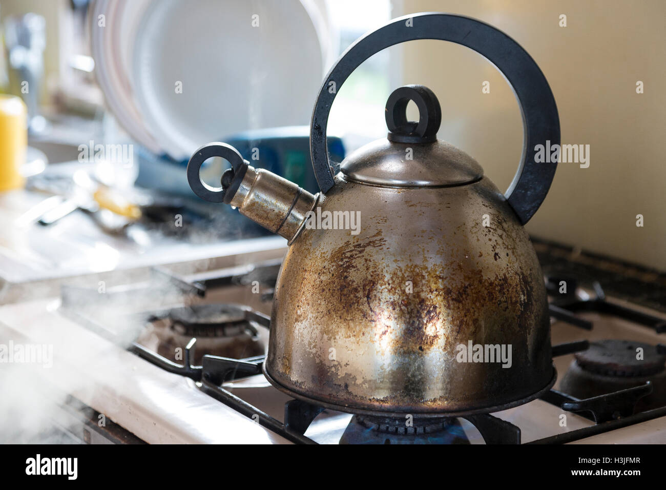 Old stainless steel kettle boiling on gas stove in caravan (trailer). Stock Photo
