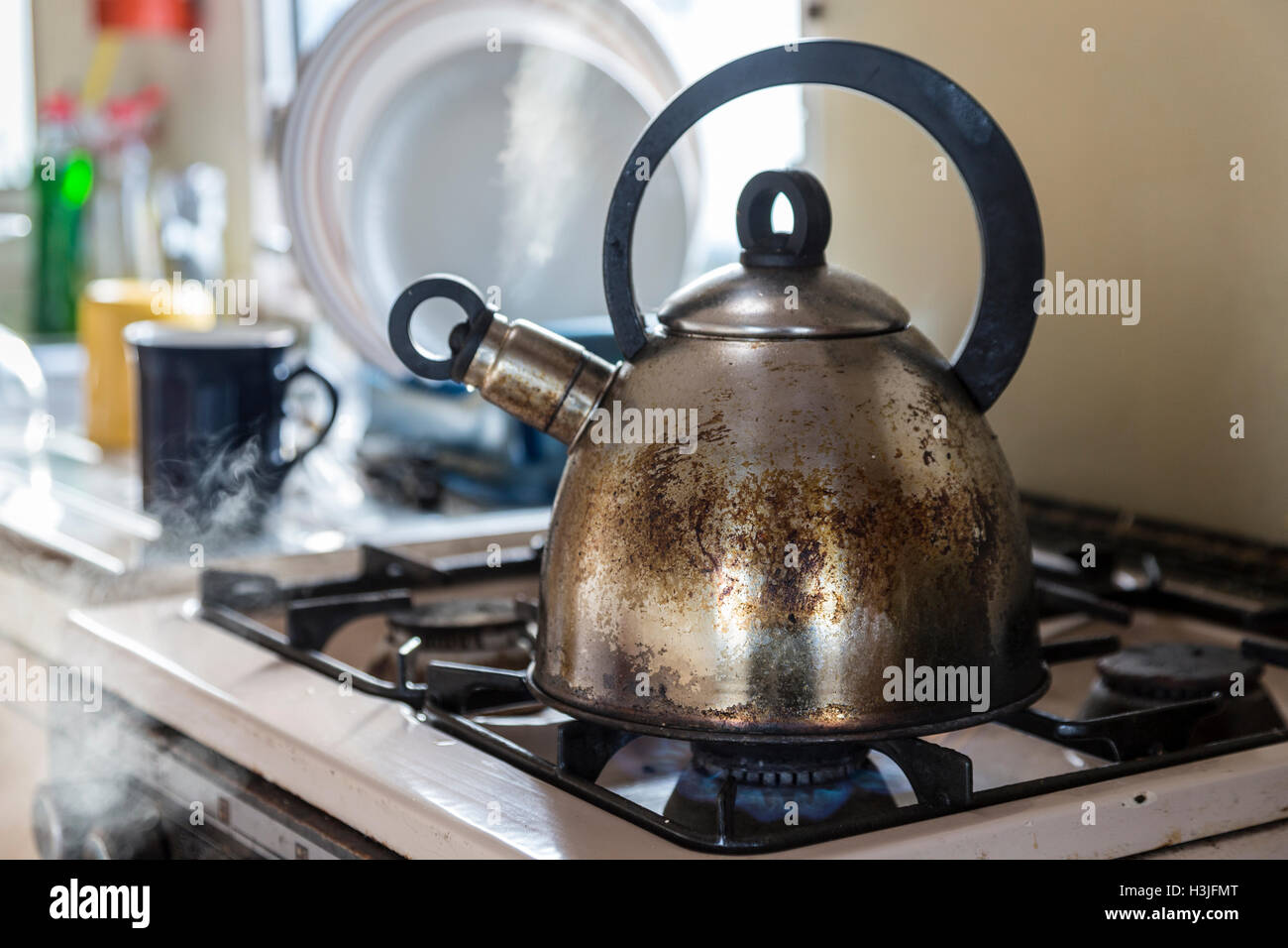 Old stainless steel kettle boiling on gas stove in caravan (trailer
