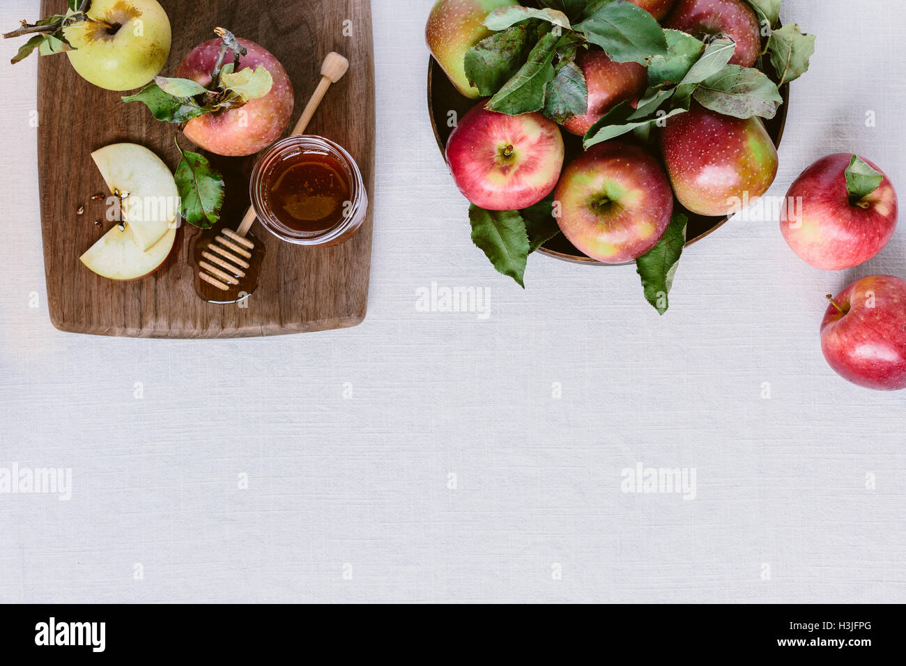 Freshly picked apples and honey are displayed on a white backdrop and photographed from the top view. Stock Photo