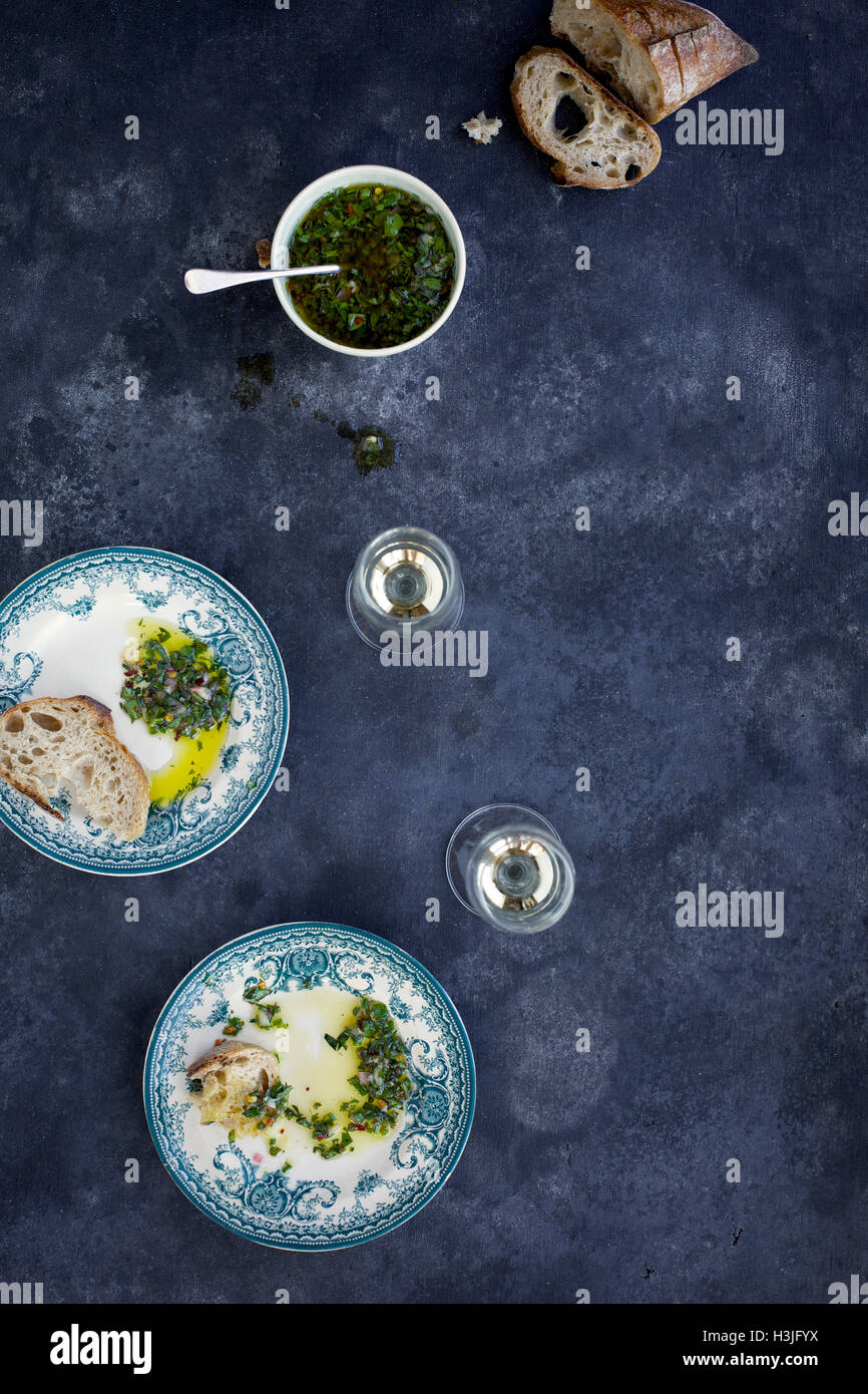 Italian Style Salsa Verde served with bread and white wine. Photographed from top view on a dark grey background. Stock Photo