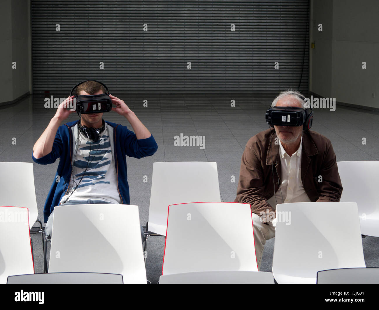 The future of visual entertainment, two men wearing VR glasses in boring and sterile environment. Cologne, Germany Stock Photo