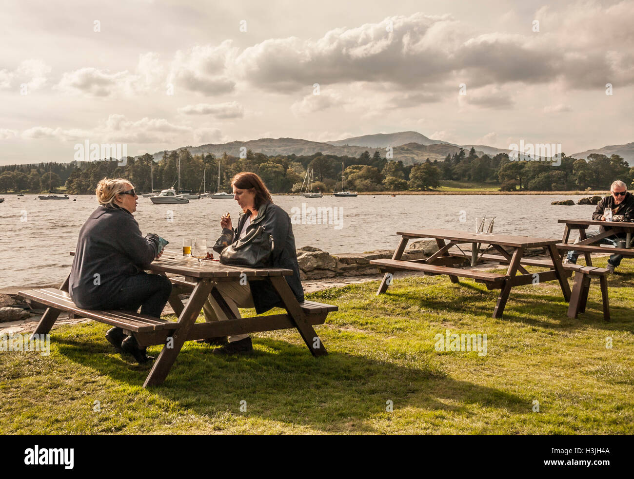 People enjoying a drink at the lakeside tables at Lake Windermere in Ambleside,Cumbria,England Stock Photo