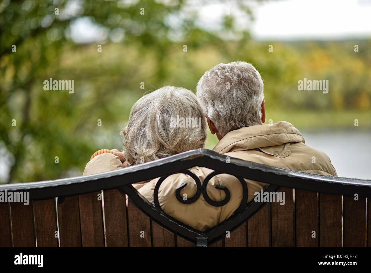 Elderly couple sitting on a bench in autumn park Stock Photo - Alamy