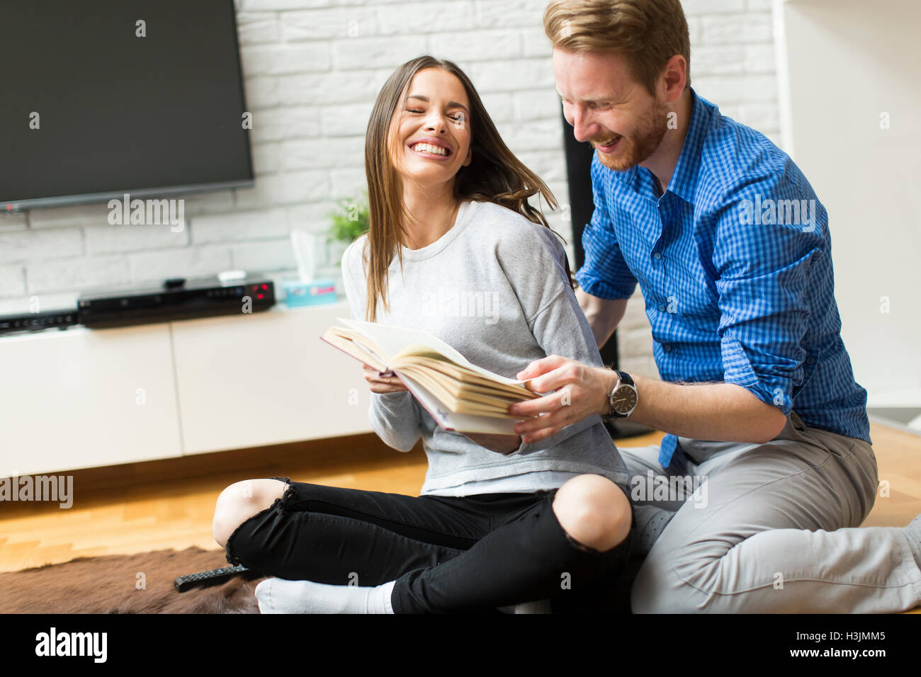 Couple with a laptop sitting on the floor Stock Photo - Alamy
