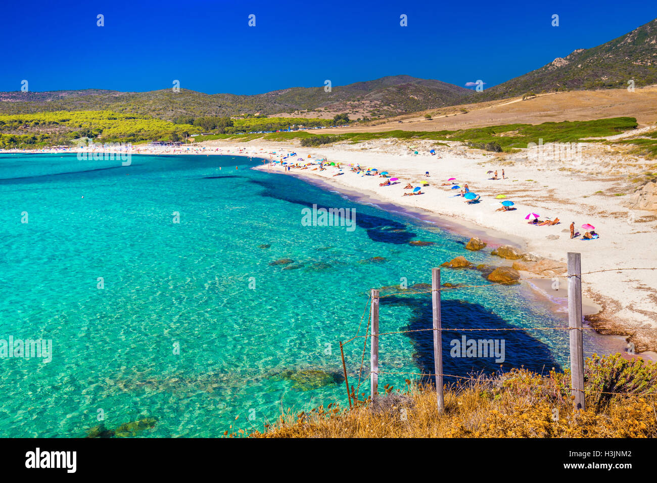 People enjoying the sunny weather on sandy Grand Capo beach with red rocks near Ajaccio, Corsica, Europe. Stock Photo