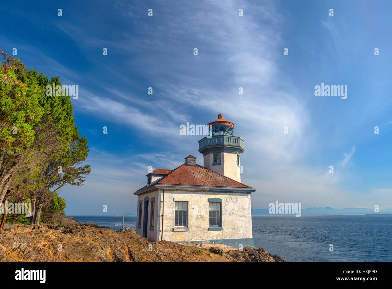USA, Washington, San Juan Island, Lime Kiln Point State Park, Lime Kiln Point Lighthouse and shoreline beneath a blue sky. Stock Photo