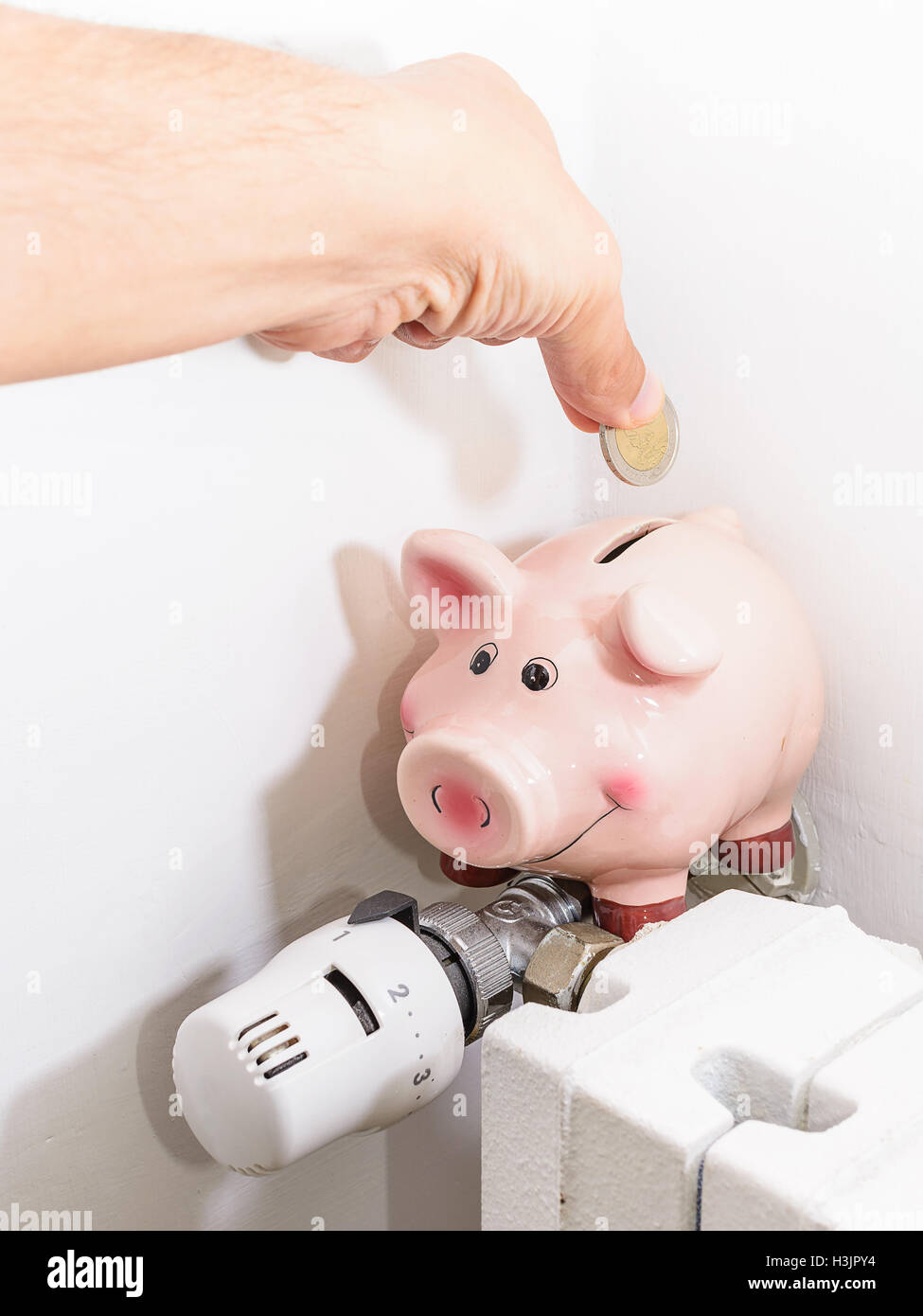 Concept Piggy, the valve on the radiator for saving energy and money Stock Photo