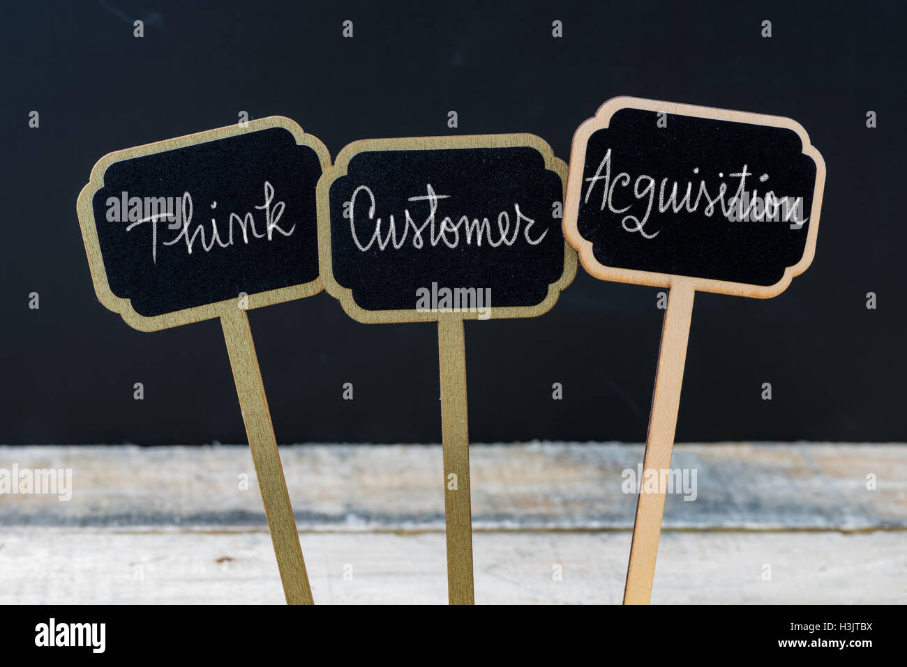 Business message THINK CUSTOMER ACQUISITION written with chalk on wooden mini blackboard labels Stock Photo