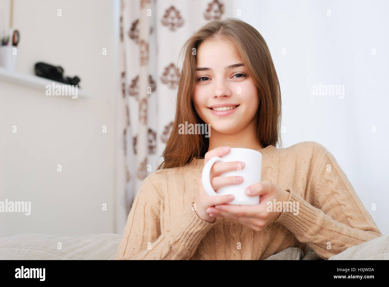 young woman sitting on couch and drinking coffee Stock Photo - Alamy