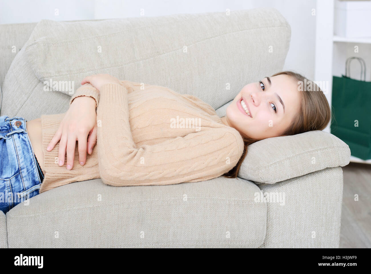 smiling young woman lying on couch Stock Photo - Alamy