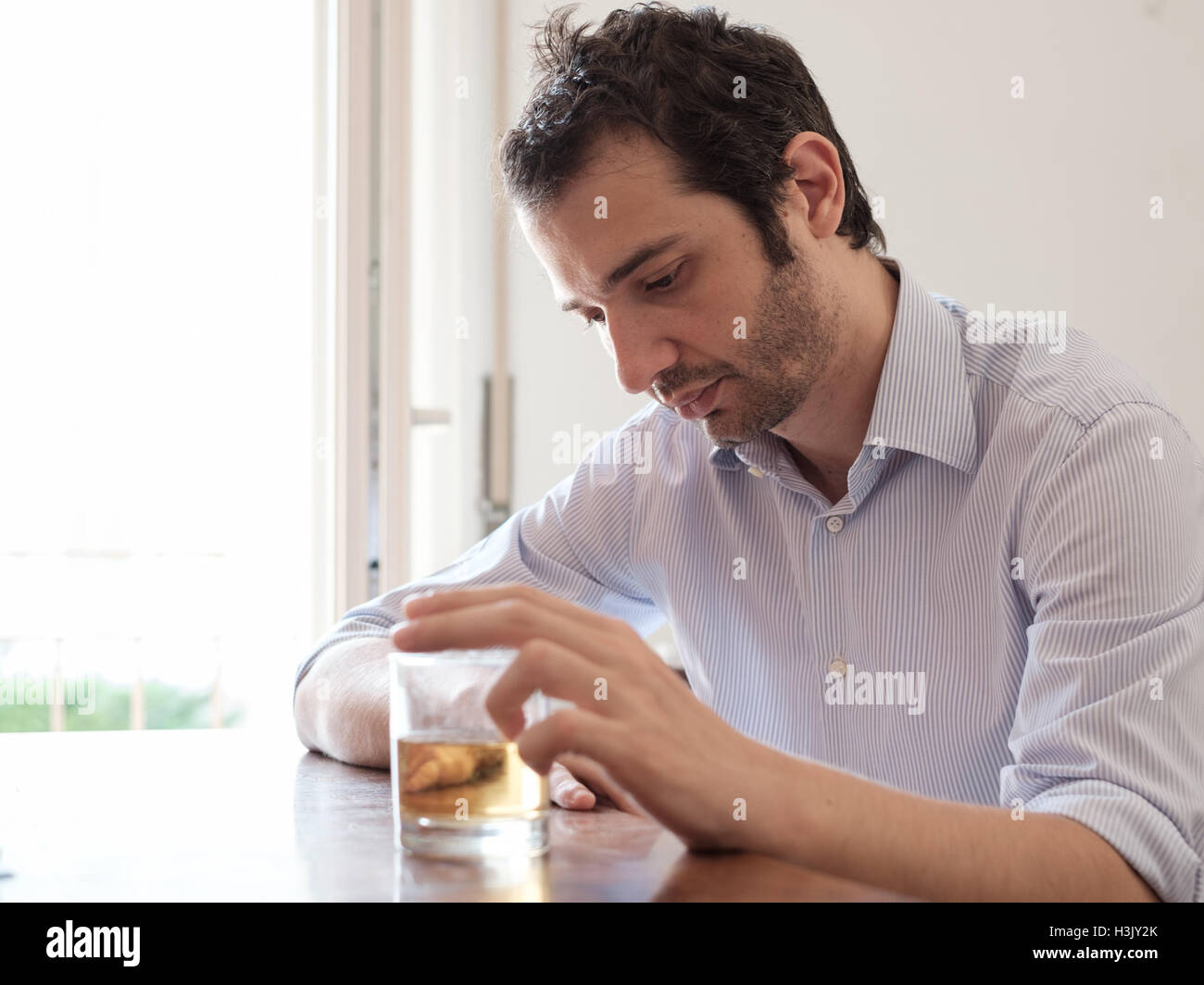 Depressed man abusing of alcohol trying to forget his problems Stock Photo